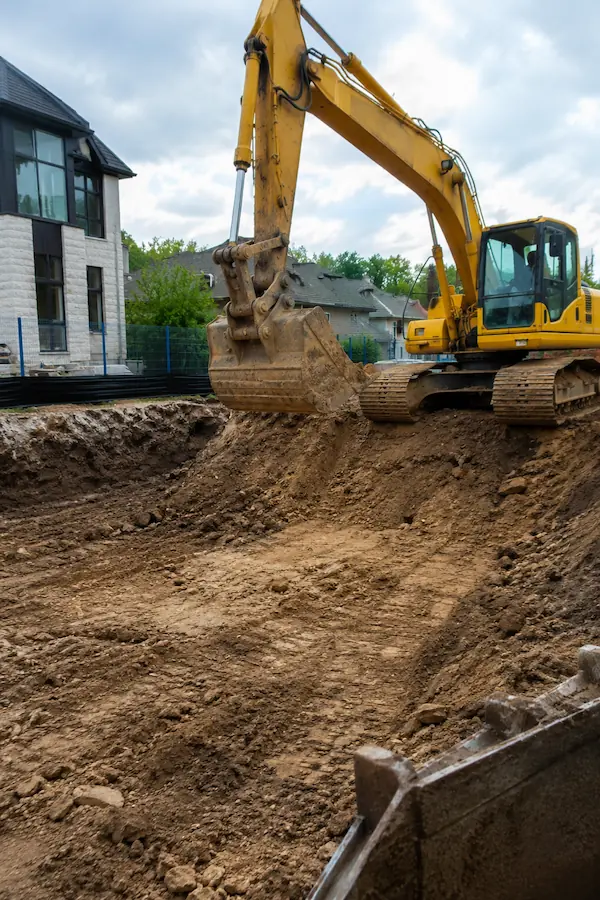 Mini excavator cutting and grading a compacted base on a Langley lot