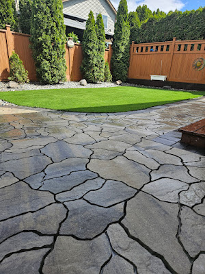 Random-pattern flagstone patio with an artificial turf inset in a Langley backyard