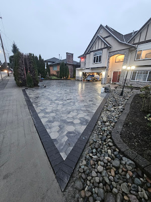 Premium interlocking paver driveway with a dark chevron border and river-rock edge at a Langley home