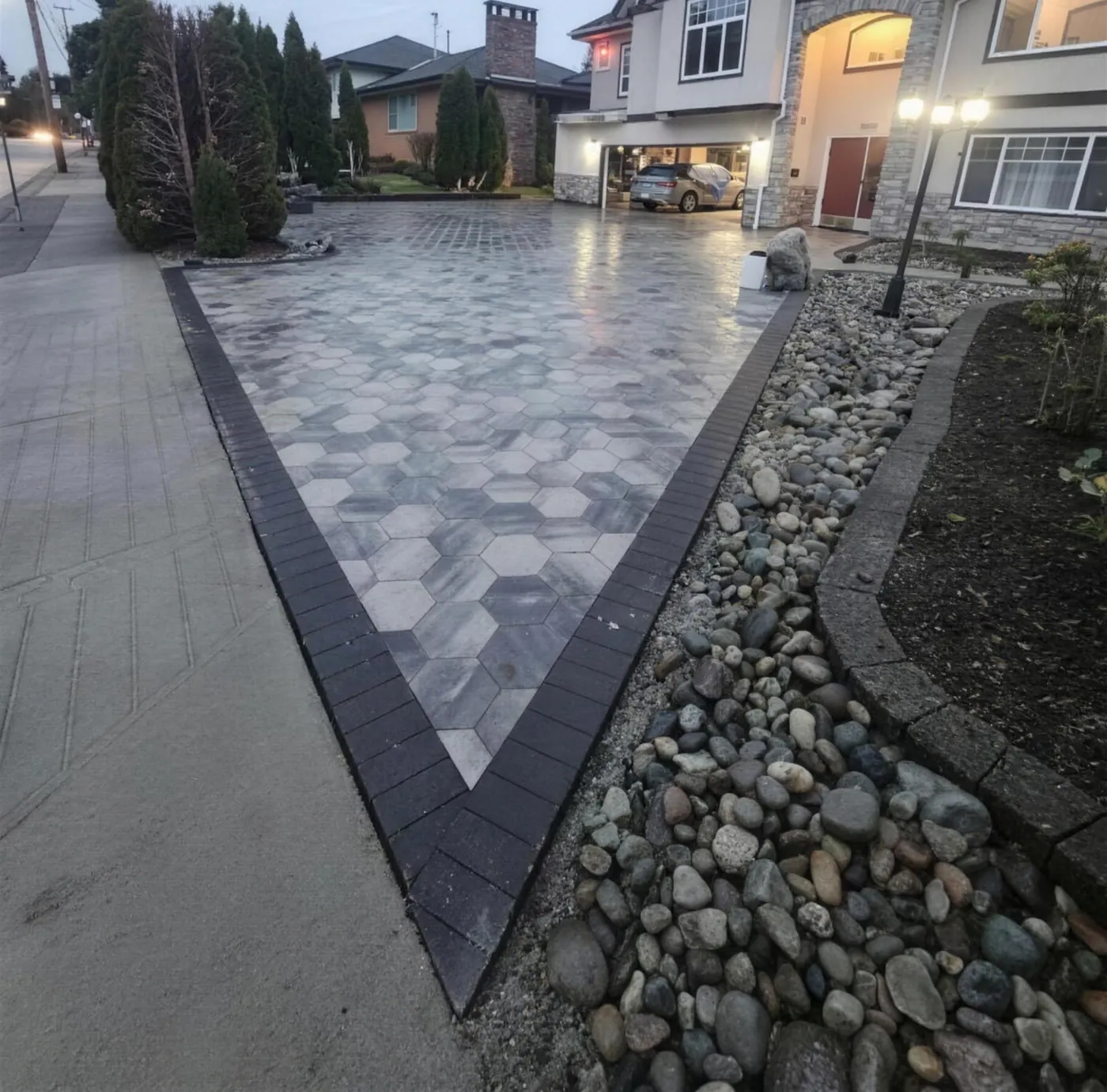 Interlocking paver driveway with a dark chevron border and river-rock edge at a Langley home by Graedyn Landscaping