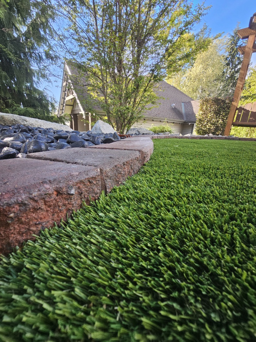 Segmental block retaining wall with a paver border and artificial turf lawn in Langley
