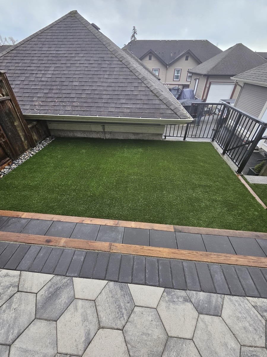 Large-format paver slab walkway beside a composite deck and artificial turf lawn in a Langley backyard
