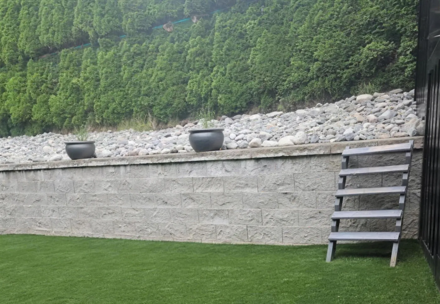 Stacked natural-stone retaining wall above an artificial turf lawn in Langley by Graedyn Landscaping